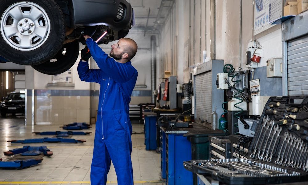 Will insurance pay for rental car during repairs - A man in blue suit repairing a car.